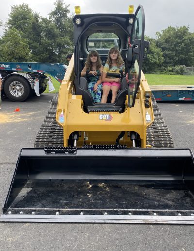 Girls posing on a bulldozer display